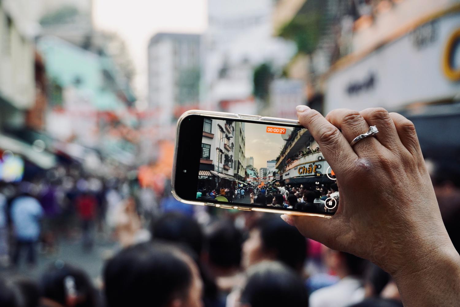Smartphone capturing a bustling urban crowd, illustrating global reach and mobile traffic