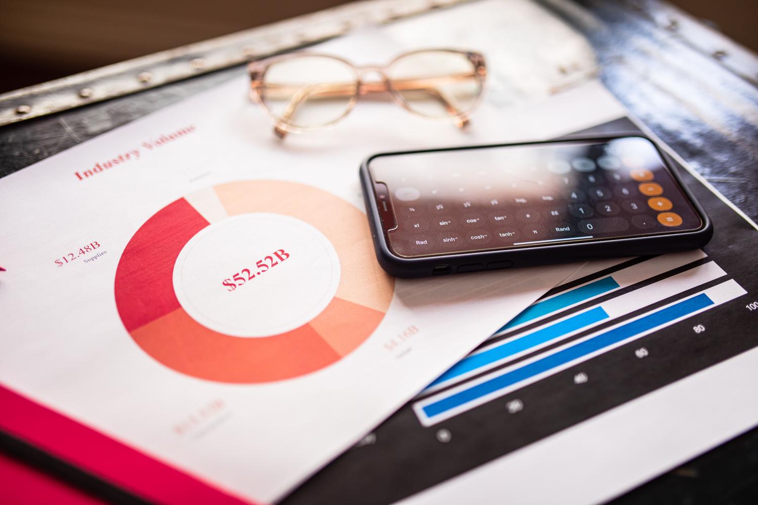 Smartphone resting on financial charts and reports representing ROI and analytics