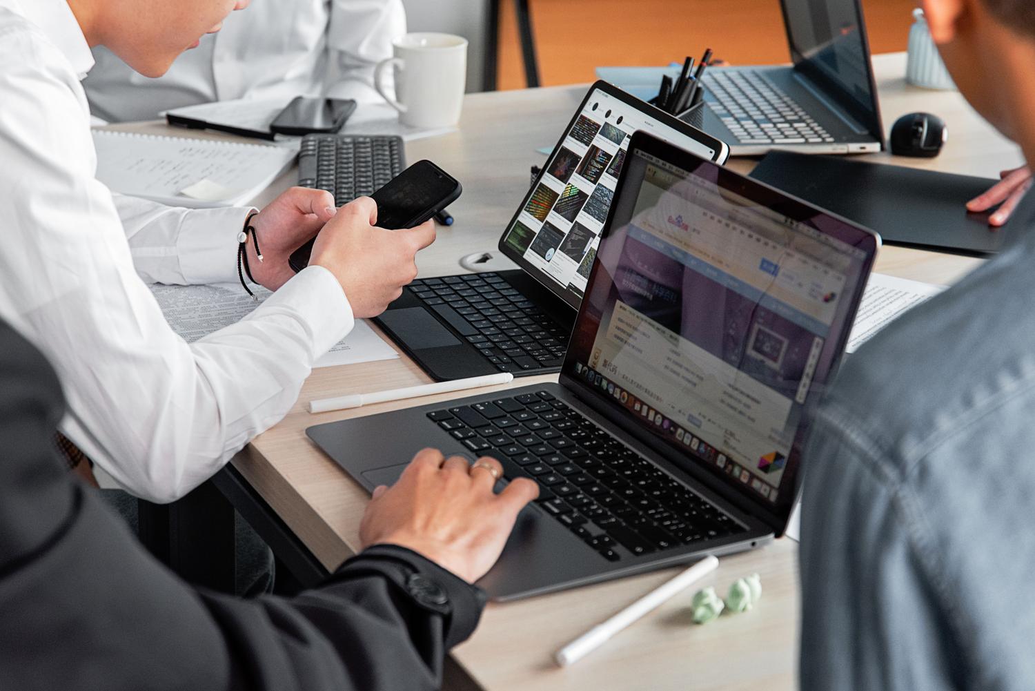 Digital marketing professionals collaborating in a modern office with smartphones and laptops