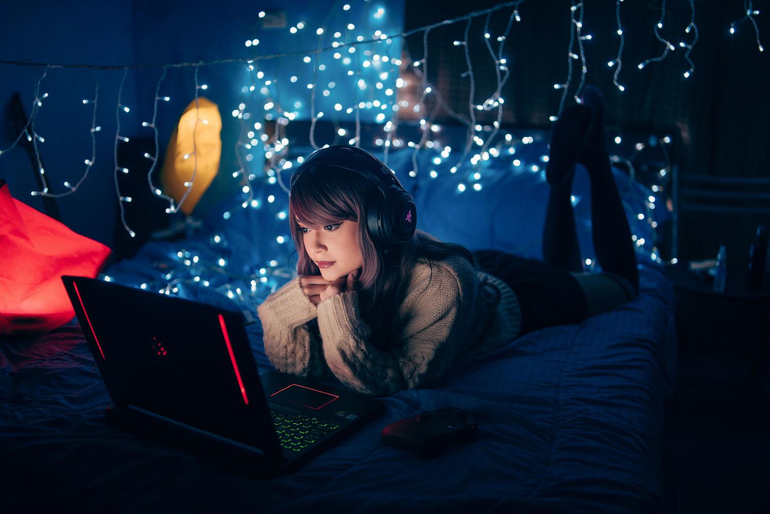 Persona sumergida en la visualización de anime con auriculares y laptop en una habitación con luces ambientales