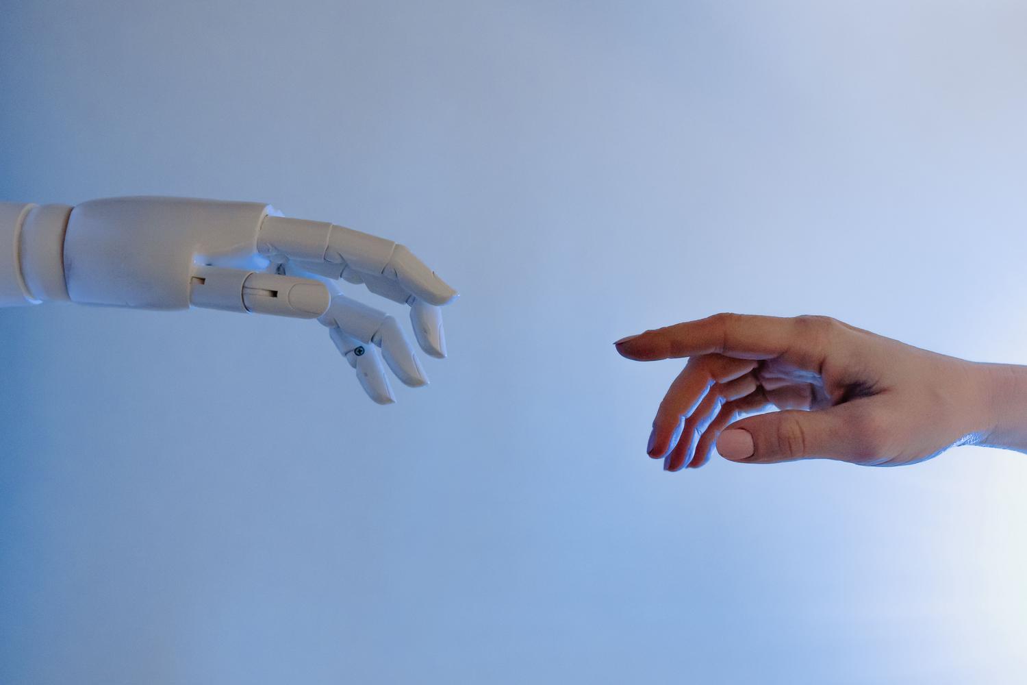 Primer plano de una mano humana y una robótica conectando, representando la colaboración y el despliegue de agentes de IA en el mundo real.