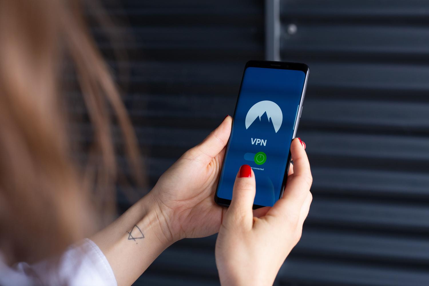 Primer plano de unas manos utilizando una aplicación de VPN en un smartphone para desbloquear contenidos móviles.