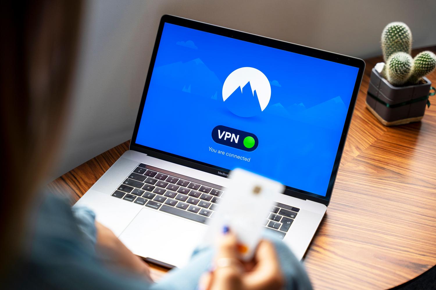 Persona utilizando una conexión VPN en un portátil sobre un escritorio de madera para navegar de forma segura.