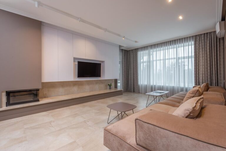 Salón moderno con sofá grande y televisor montado en la pared, ideal para ilustrar la distancia de visionado.