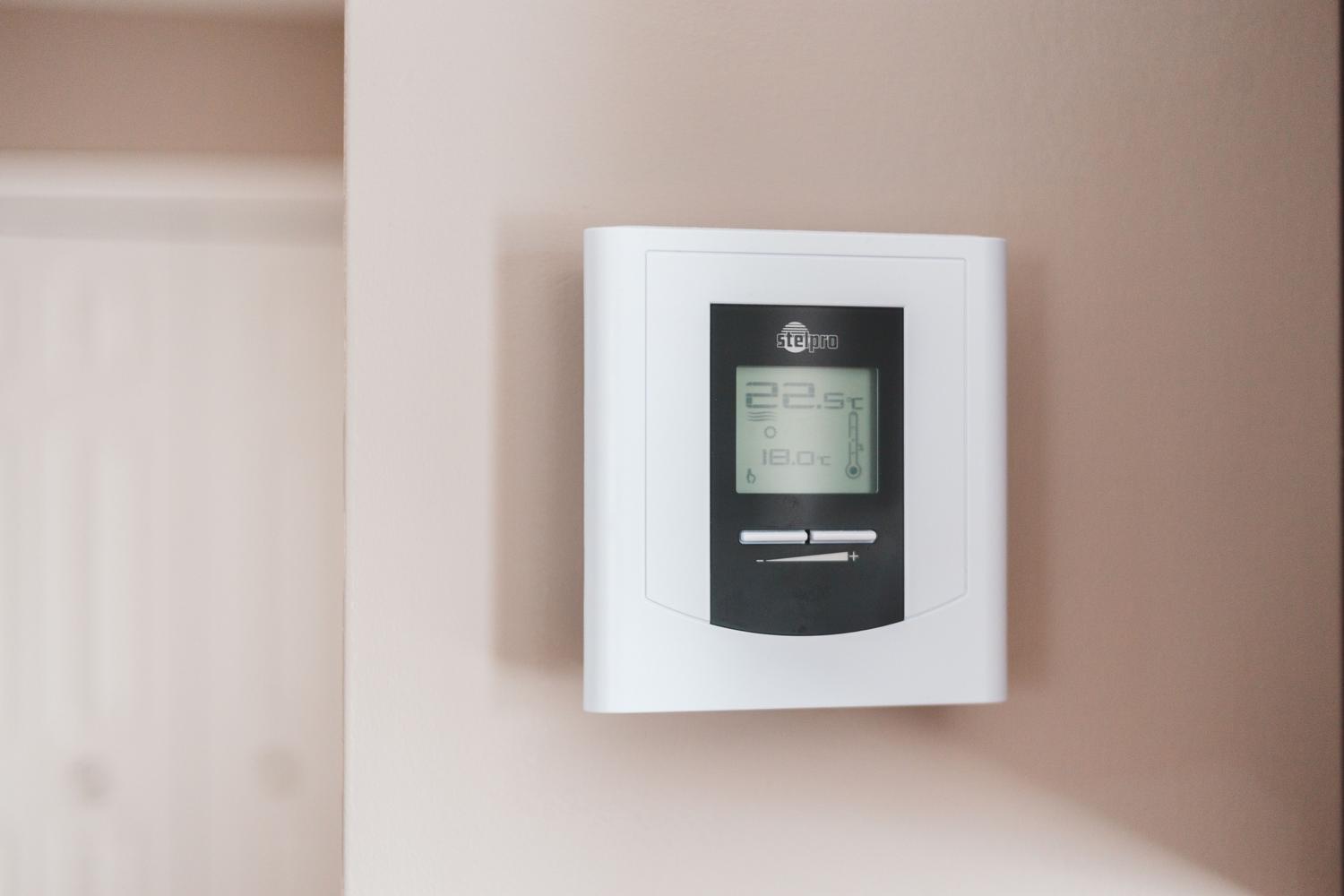 Termostato digital moderno en una pared, ejemplo de domótica sostenible para optimizar la climatización y reducir el consumo eléctrico.