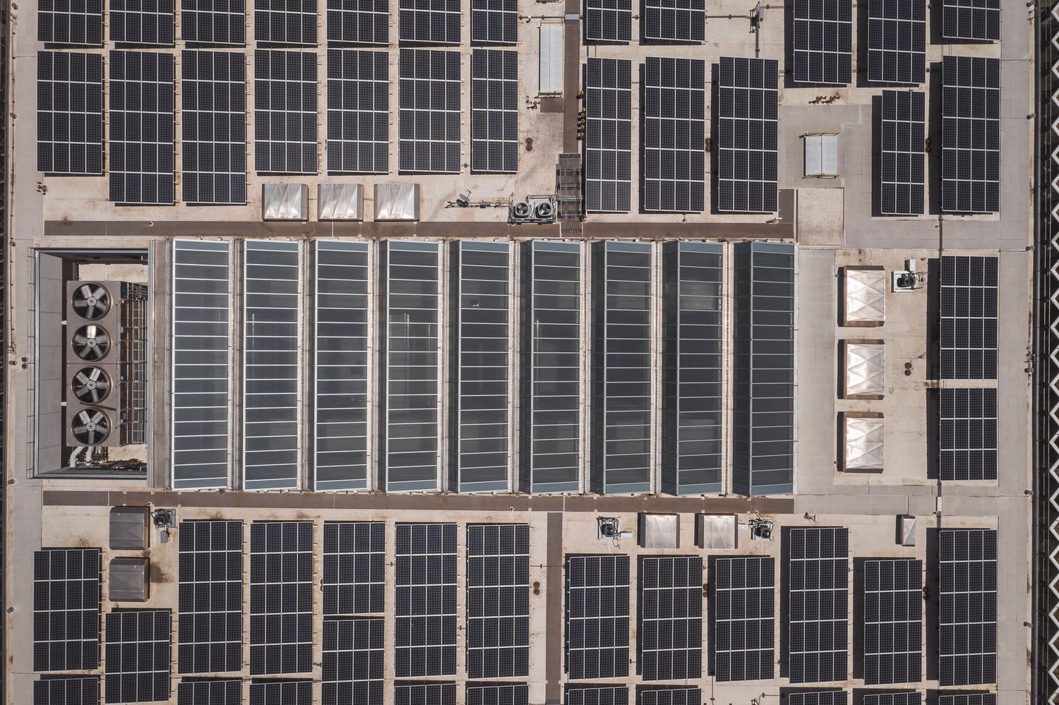 Vista aérea de paneles solares instalados en el techo de un edificio industrial, ilustrando el uso de energías renovables para alimentar centros de datos.
