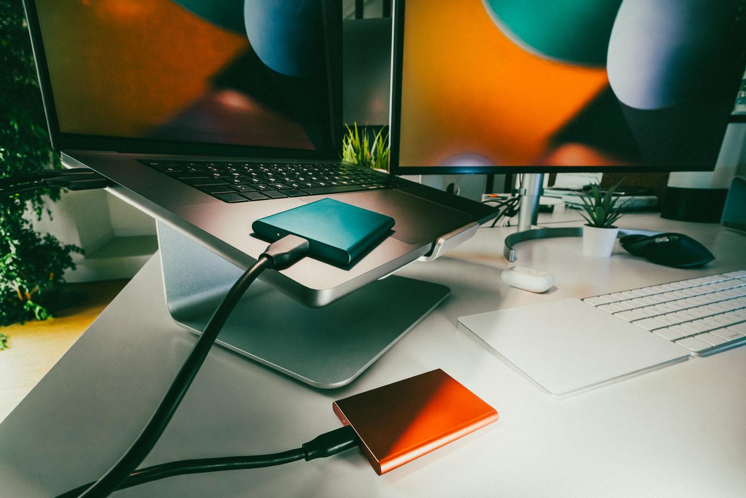 Configuración de estudio en casa con un portátil y unidades de almacenamiento externo para el respaldo de datos.