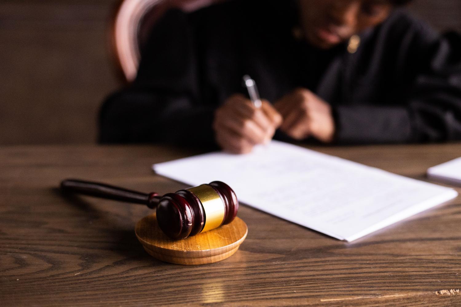 Juez firmando documentos legales junto a un mazo, representando las sentencias y disputas judiciales sobre derechos de autor.