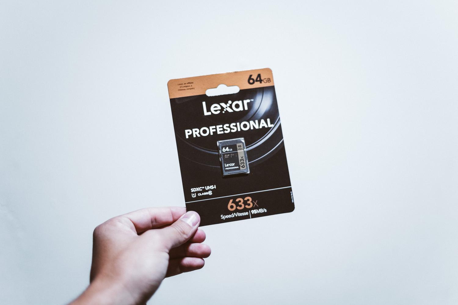 Primer plano de una mano sosteniendo una tarjeta microSD de 64GB, esencial para ampliar el almacenamiento de un móvil Android.