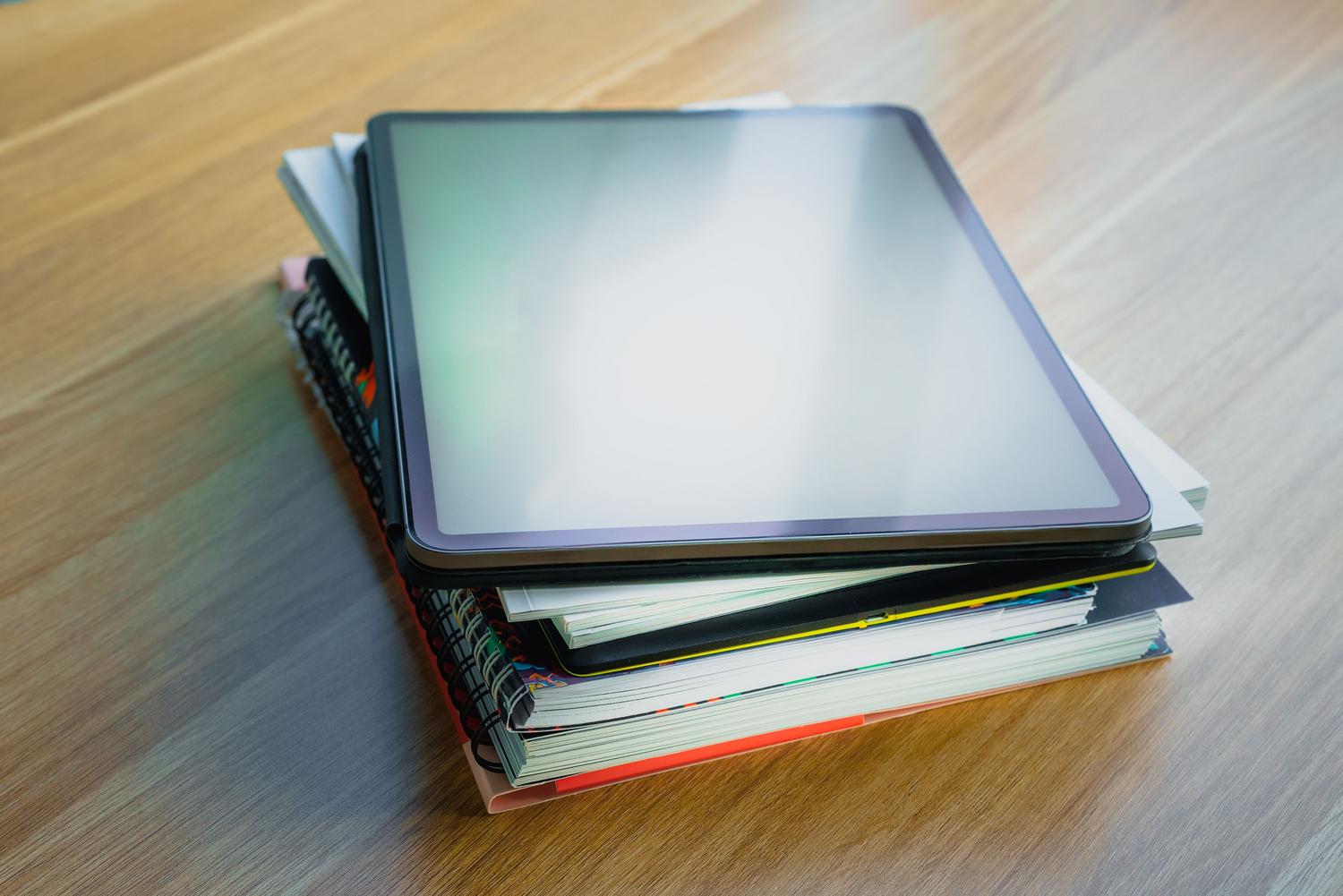 Tablet digital sobre una pila de libros, representando la transición de una biblioteca física a una digital gestionada por Calibre.