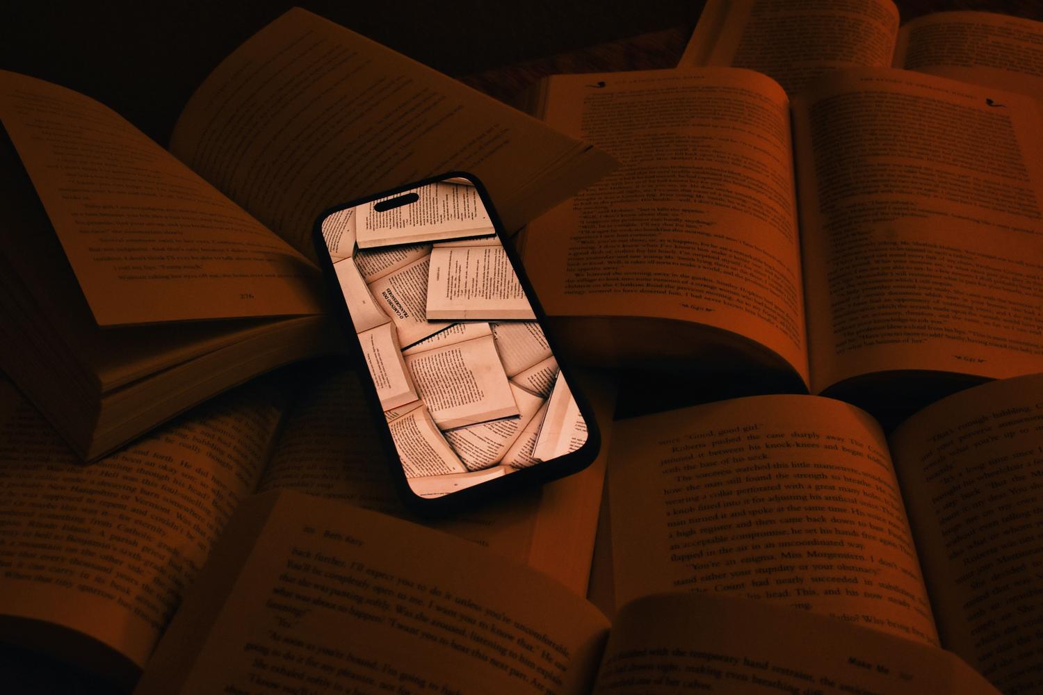 Smartphone mostrando páginas digitales sobre libros abiertos, simbolizando la integración de la lectura digital y física.