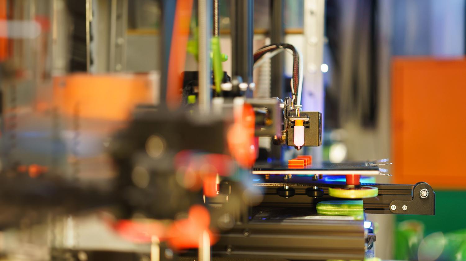 Impresora 3D fabricando un prototipo técnico en un entorno de taller, ilustrando la manufactura aditiva.