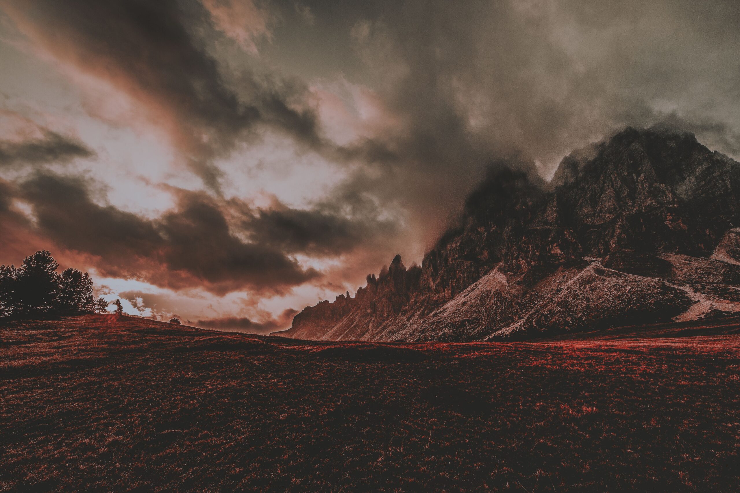 Montañas majestuosas bajo un cielo dramático, representando la escala colosal de los escenarios del juego.