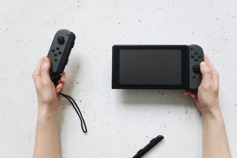 Manos sosteniendo una consola Nintendo Switch en un fondo blanco, representando la plataforma principal de la saga.