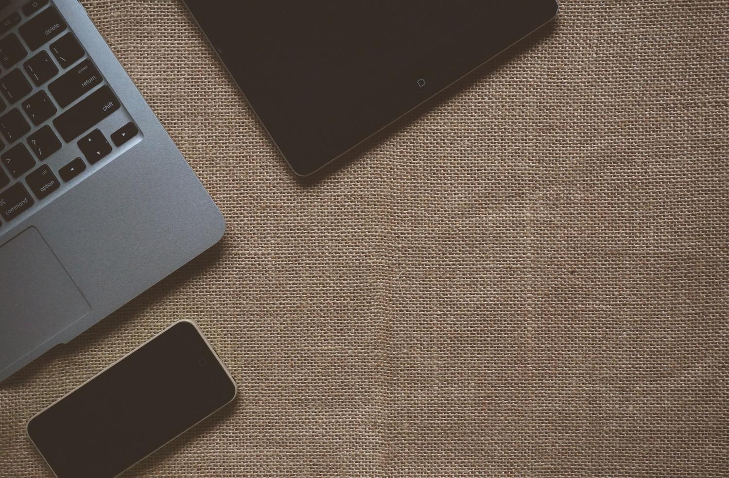 Conjunto de laptop, tablet y smartphone sobre una superficie texturizada, ilustrando la versatilidad de la IA para ejecutarse localmente en diversos dispositivos.
