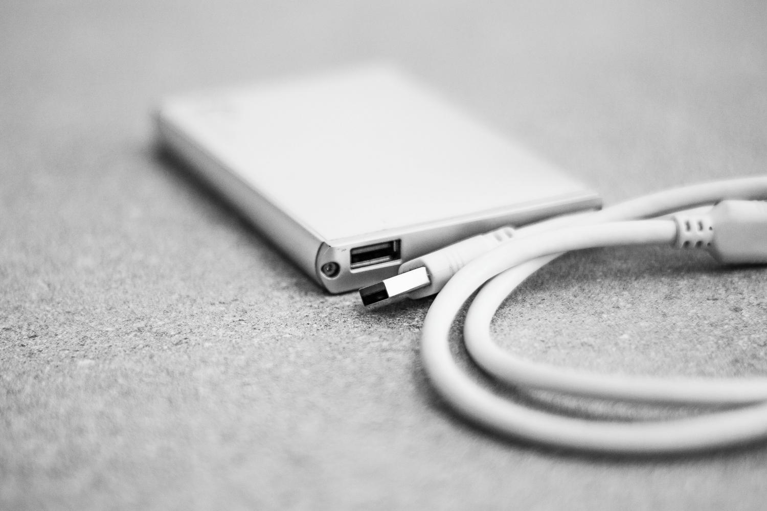 Primer plano de un disco duro externo y su cable USB, representando el hardware de almacenamiento