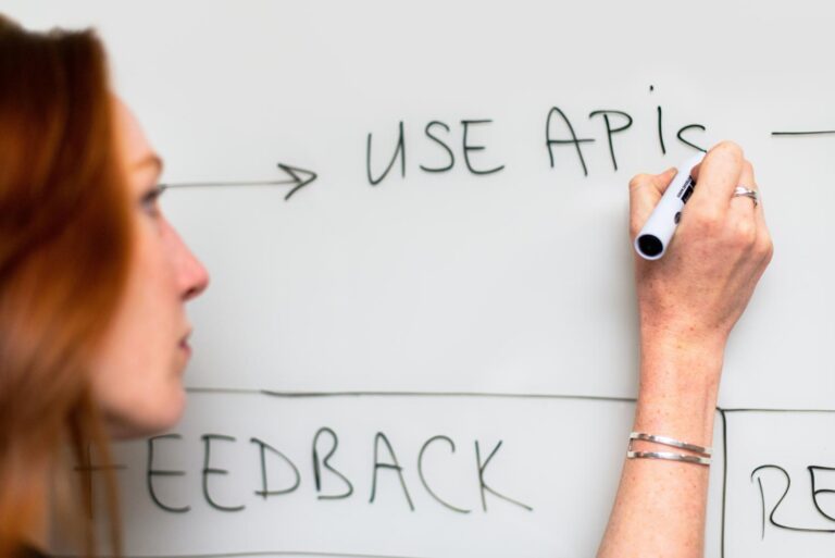 Persona planificando la arquitectura de software escribiendo 'USE APIs' en una pizarra.