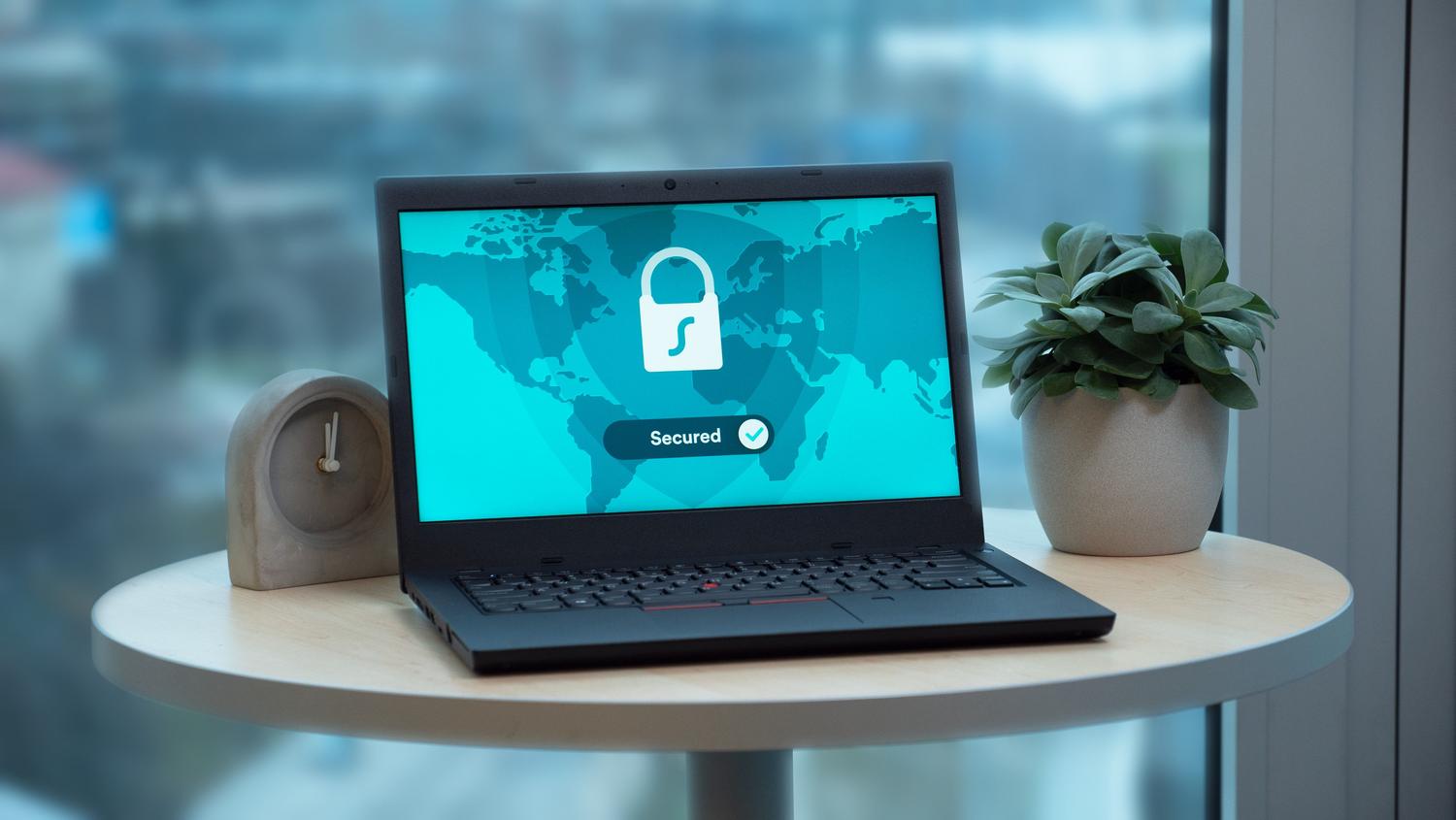 Portátil en un escritorio moderno mostrando un icono de candado y la palabra 'Secured', representando el objetivo final de un escaneo de vulnerabilidades: la seguridad confirmada.
