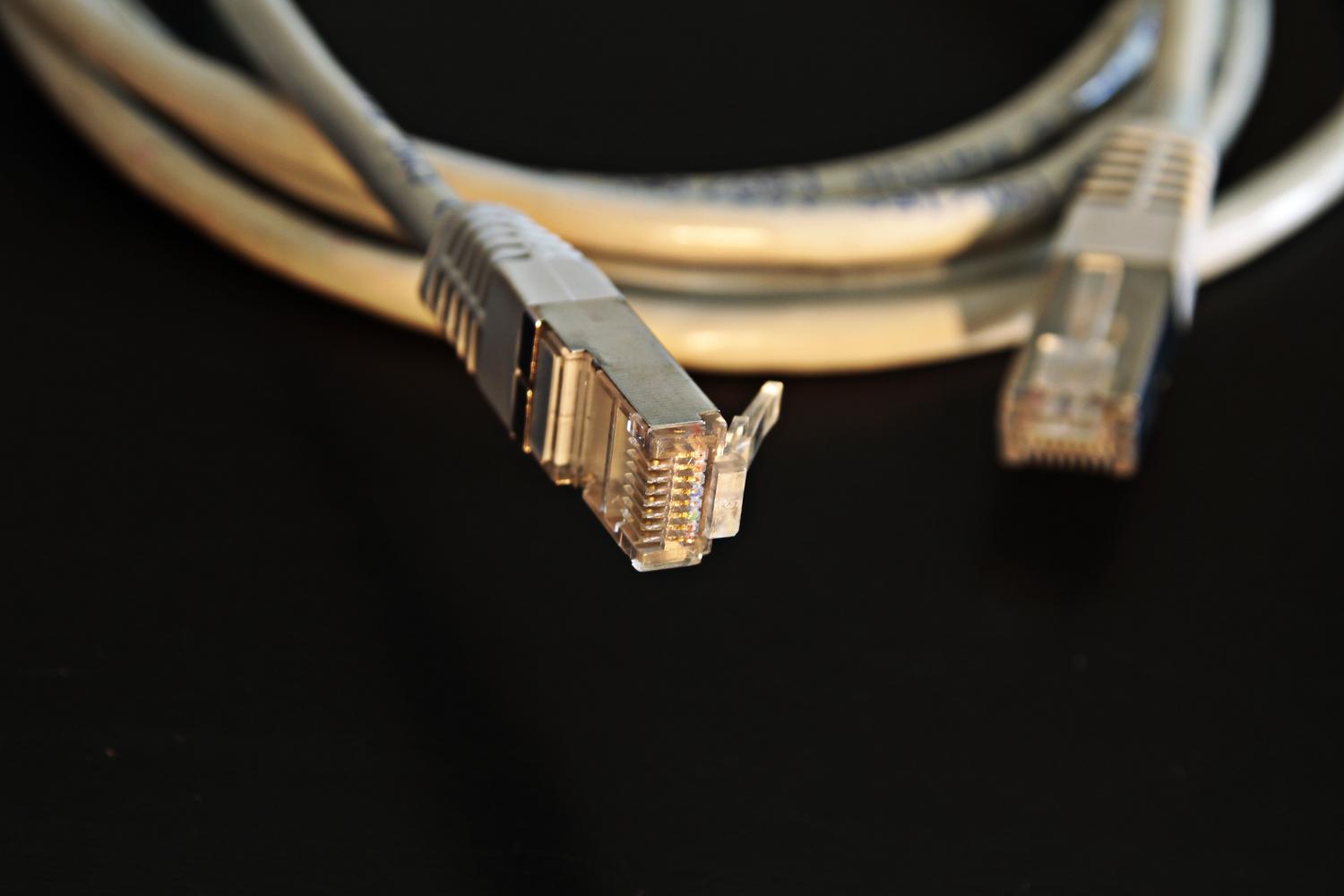 Primer plano detallado de un conector de cable Ethernet RJ45, representando la acción de desconectar el dispositivo de la red.