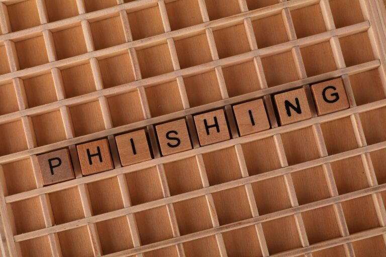 Letras de madera formando la palabra 'PHISHING' sobre un tablero, representando el concepto de ciberataque por suplantación de identidad.