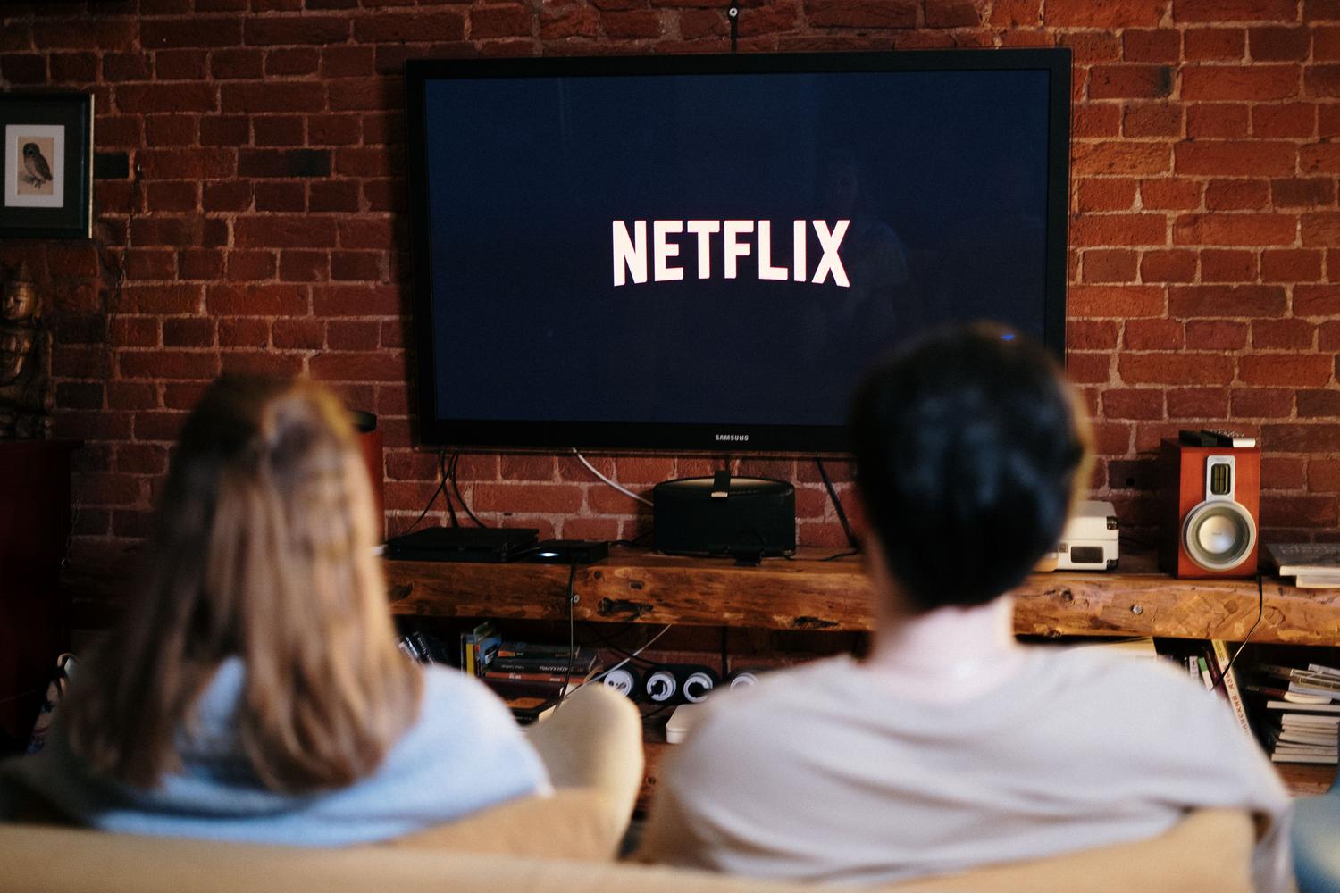 Una pareja relajándose en el sofá mientras ven una serie en la televisión en un salón acogedor.