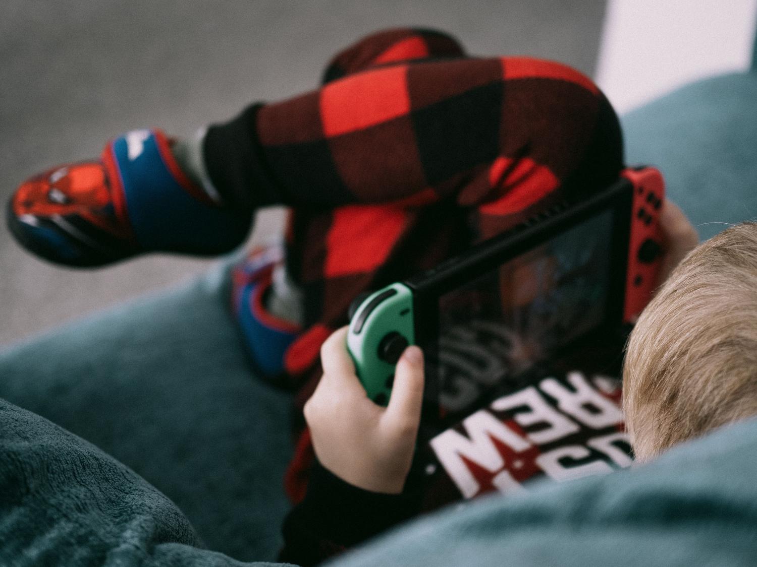 Niño jugando con una consola Nintendo Switch en el sofá de casa, concentrado en el juego.