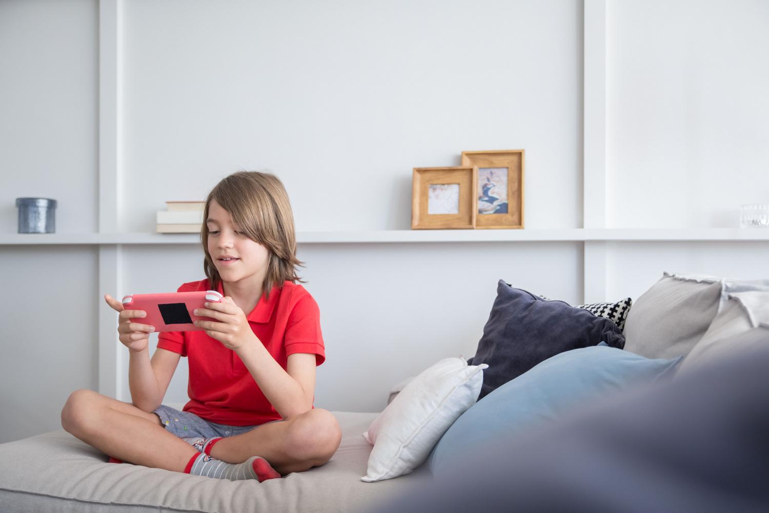 Niño jugando a un videojuego en un salón luminoso, mostrando un uso saludable y equilibrado de la tecnología.