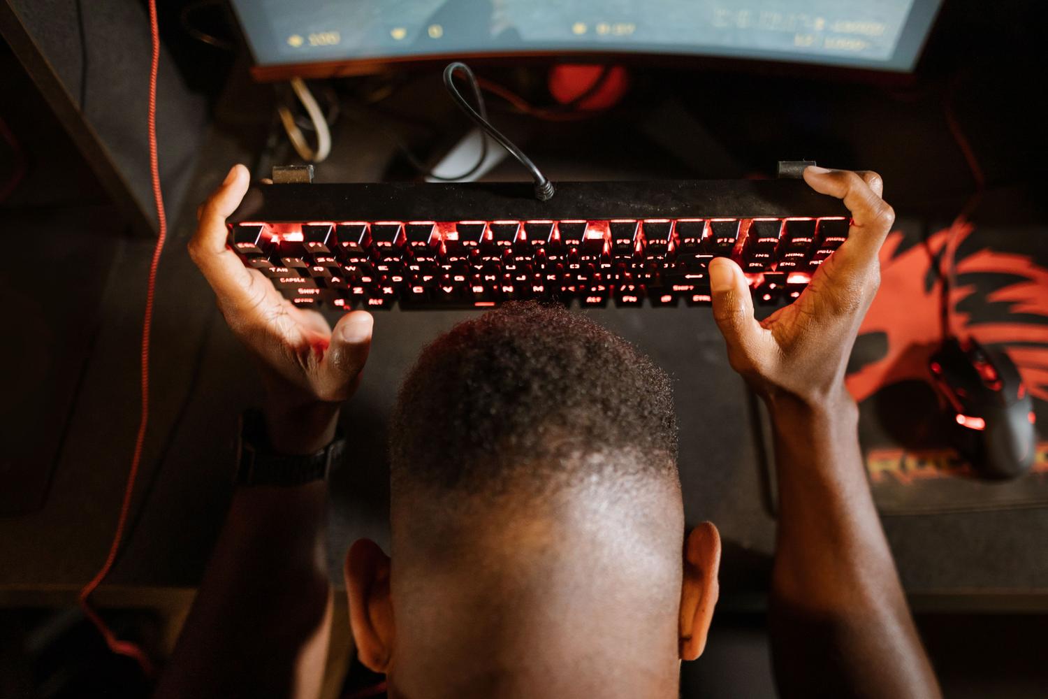 Persona sosteniendo un teclado en un momento de frustración, representando el desafío de la resiliencia y la gestión emocional en el gaming competitivo.