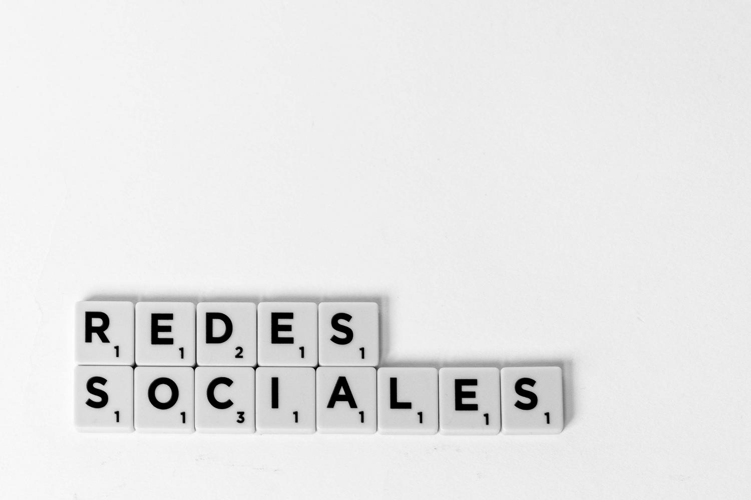 Letras de Scrabble formando la frase Redes Sociales sobre un fondo blanco, concepto minimalista de marketing digital.