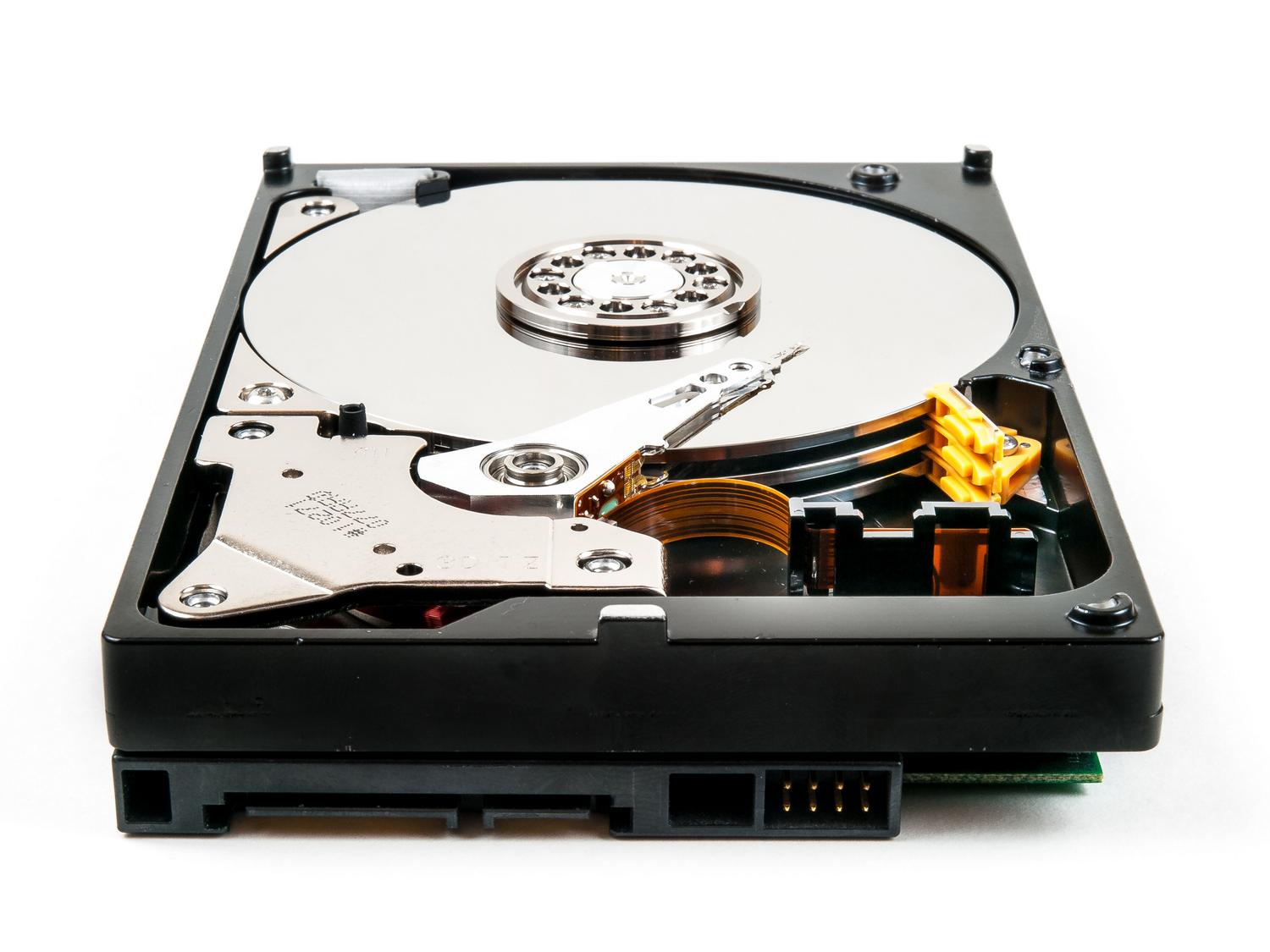 Vista detallada de los componentes internos de un disco duro mecánico (HDD) sobre fondo blanco.