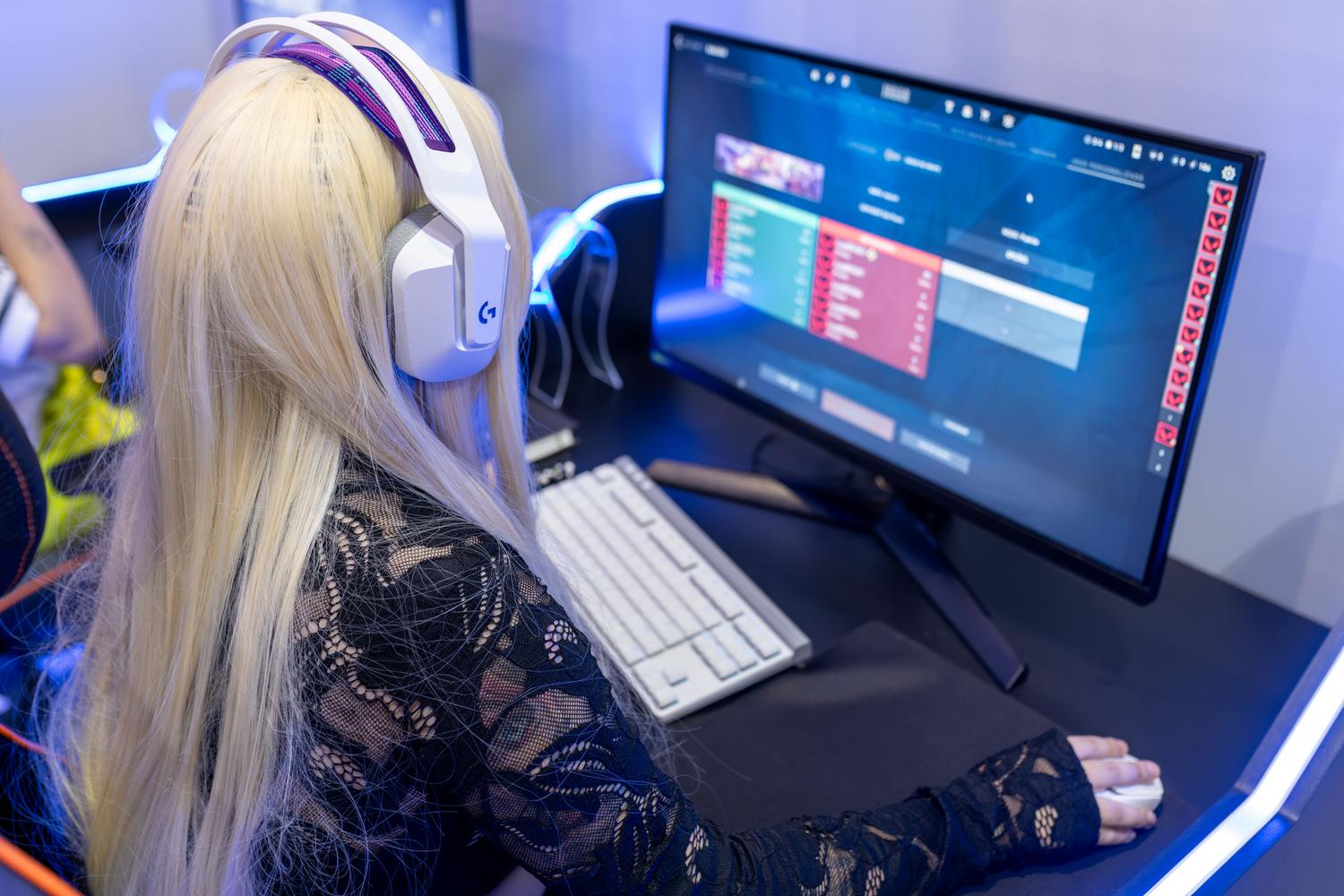Persona jugando en un ordenador con setup tecnológico avanzado y auriculares.