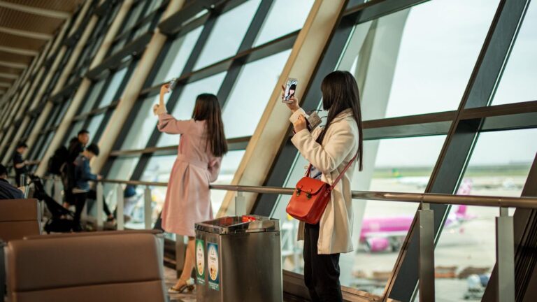 Viajeros utilizando sus smartphones en la terminal del aeropuerto de Shanghái para conectarse a internet al llegar.
