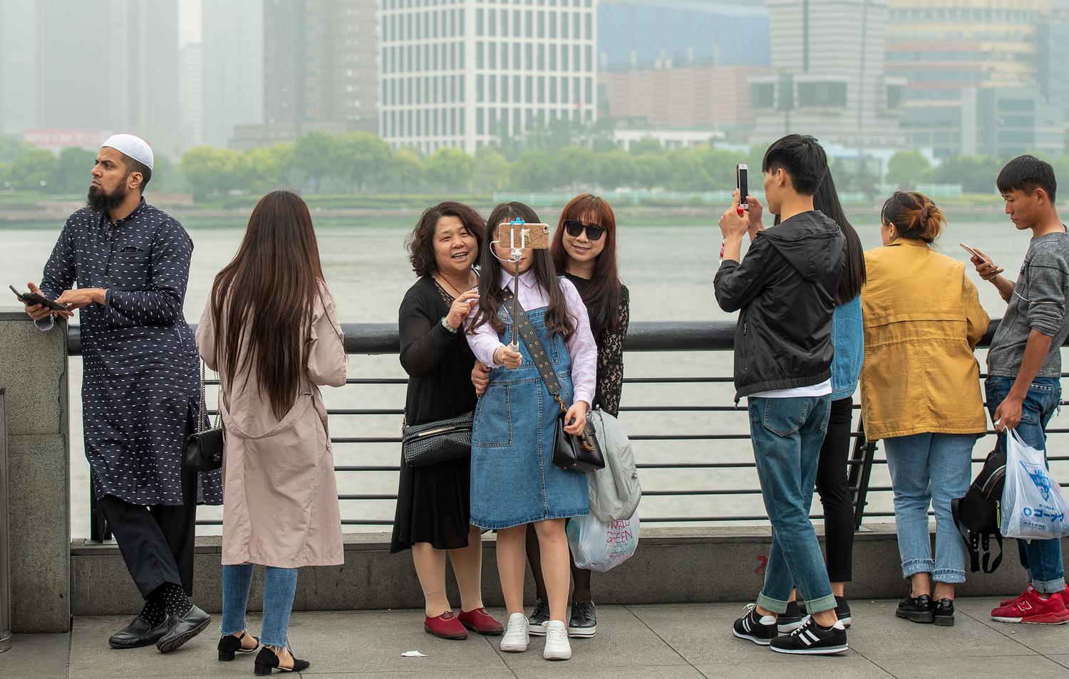 Turistas disfrutando del paseo marítimo de Shanghái, utilizando la tecnología móvil para orientarse en la ciudad.