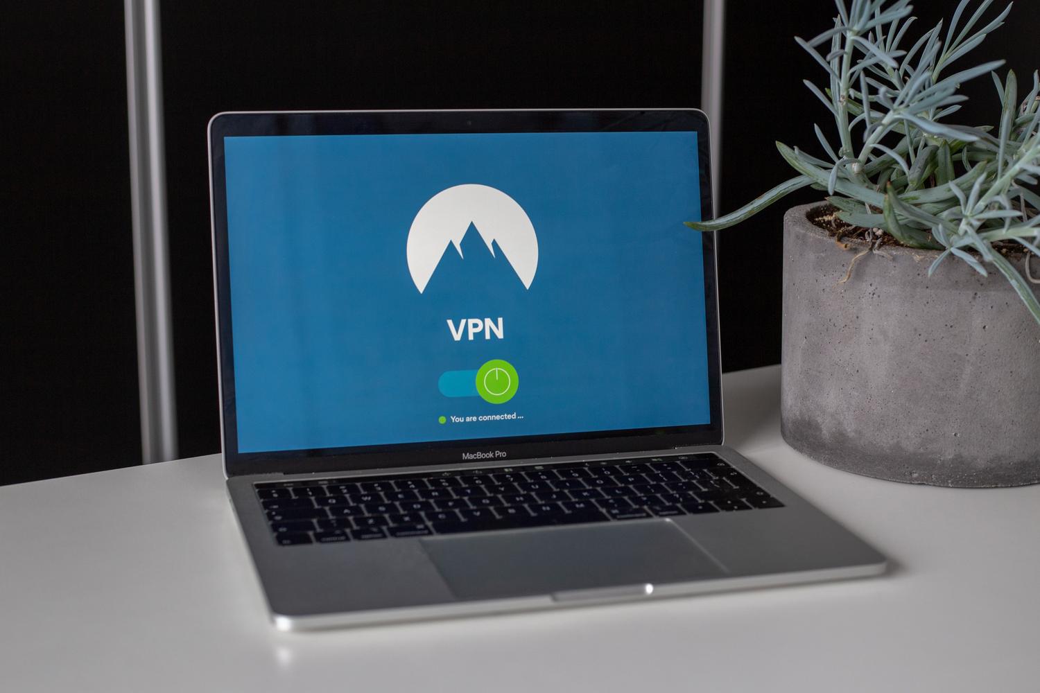 Portátil en un escritorio con una aplicación de VPN activada, representando la seguridad y privacidad en la navegación web.