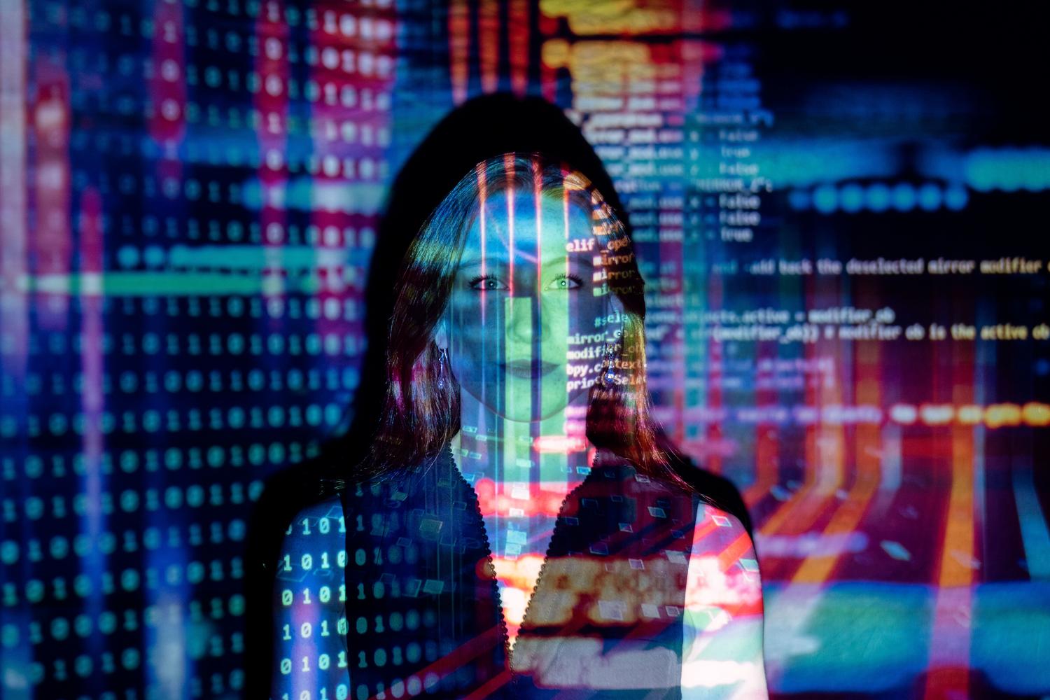 Mujer con proyecciones de código digital en su rostro, representando la fusión entre el ser humano y la inteligencia artificial en el futuro de IT