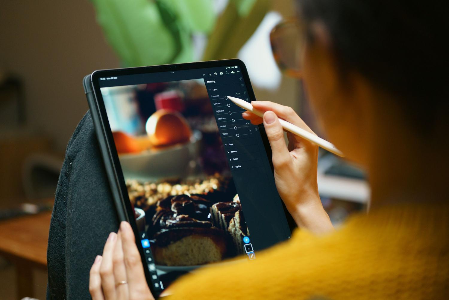 Primer plano de una persona utilizando un lápiz digital sobre una tableta para retocar con precisión una fotografía de comida.