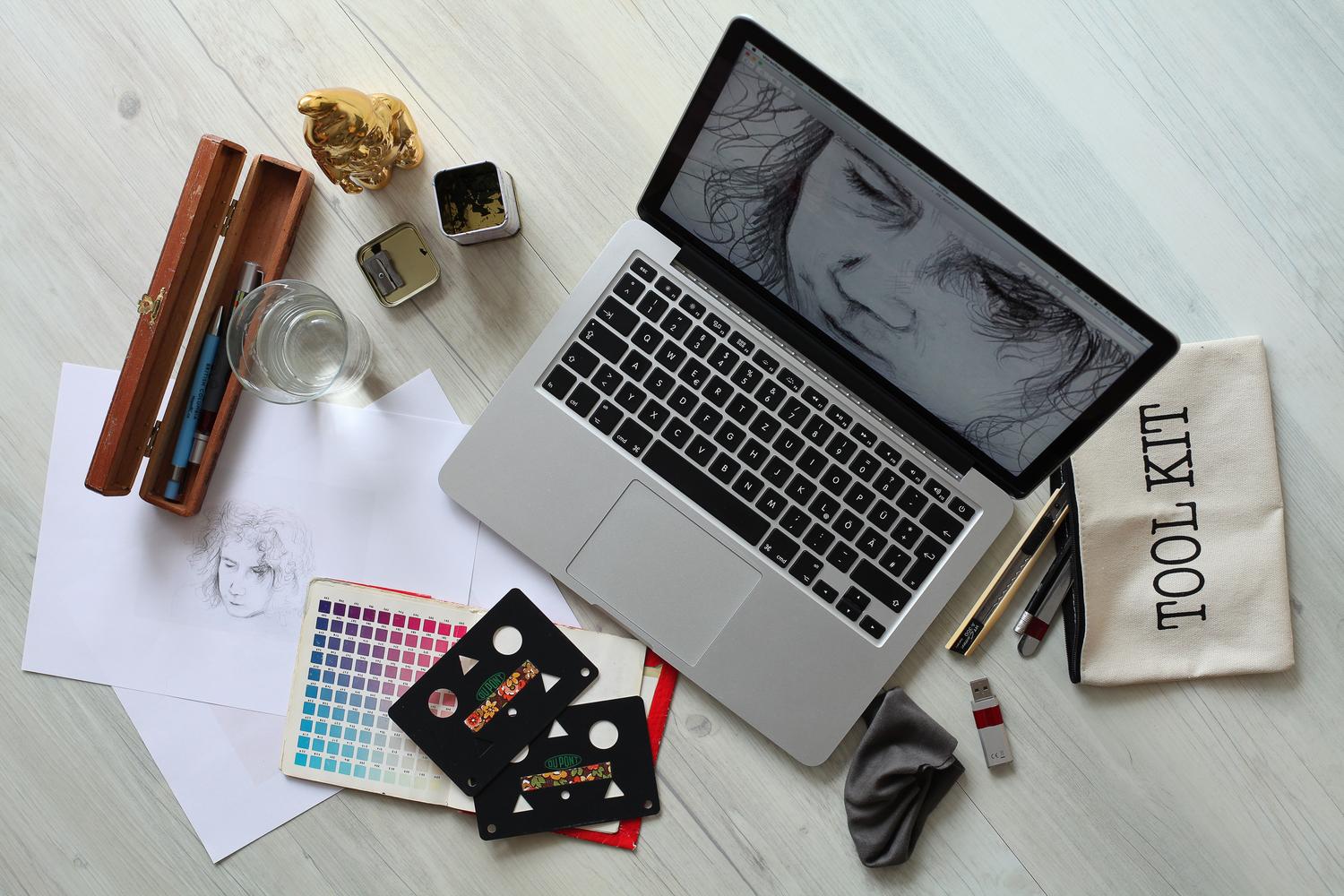 Vista cenital de un escritorio creativo con laptop, paleta de colores física y bocetos, representando la gestión del color.
