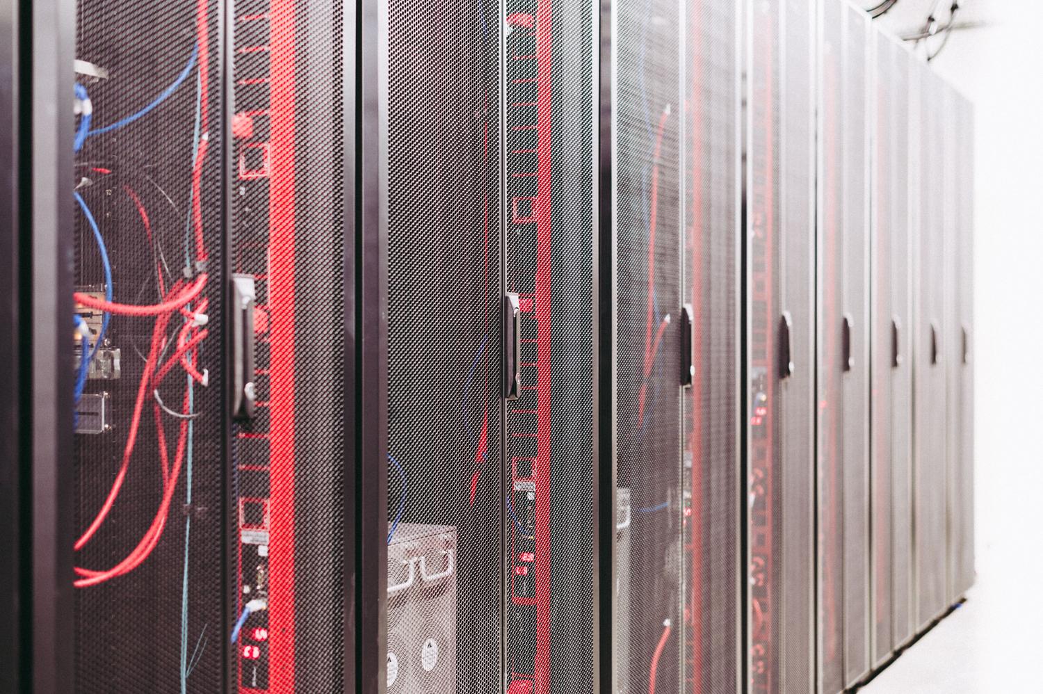 Vista de racks de servidores con un complejo sistema de cableado rojo y azul, ilustrando la interconexión de procesos técnicos.
