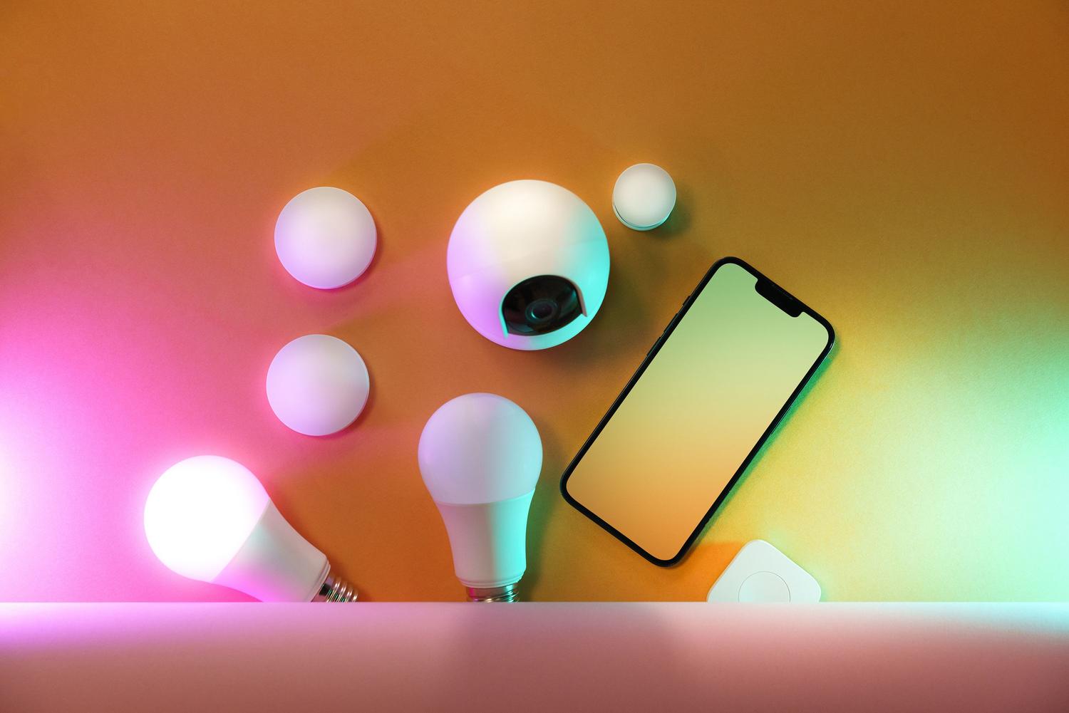 Conjunto de bombillas inteligentes y un smartphone, ilustrando la gestión de la luz mediante aplicaciones móviles.