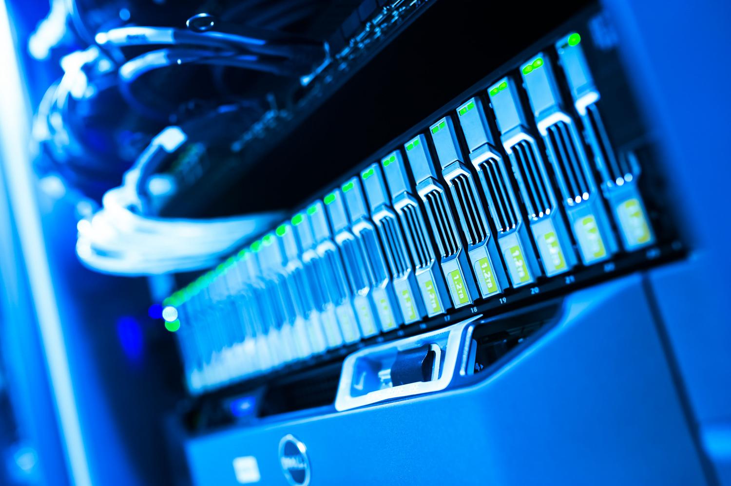Primer plano de una matriz de almacenamiento de servidores en un centro de datos con iluminación azul, simbolizando la infraestructura física y los costes de almacenamiento en un clúster de Kubernetes.