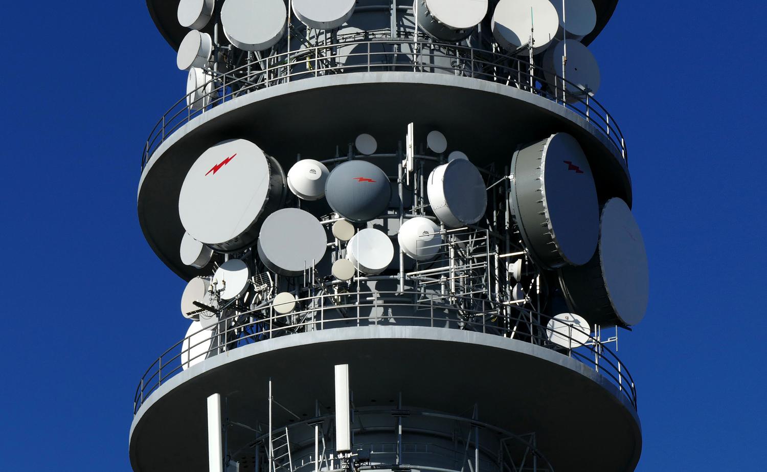 Primer plano de antenas y platos satelitales en una torre de telecomunicaciones, detallando la tecnología de transmisión de datos.