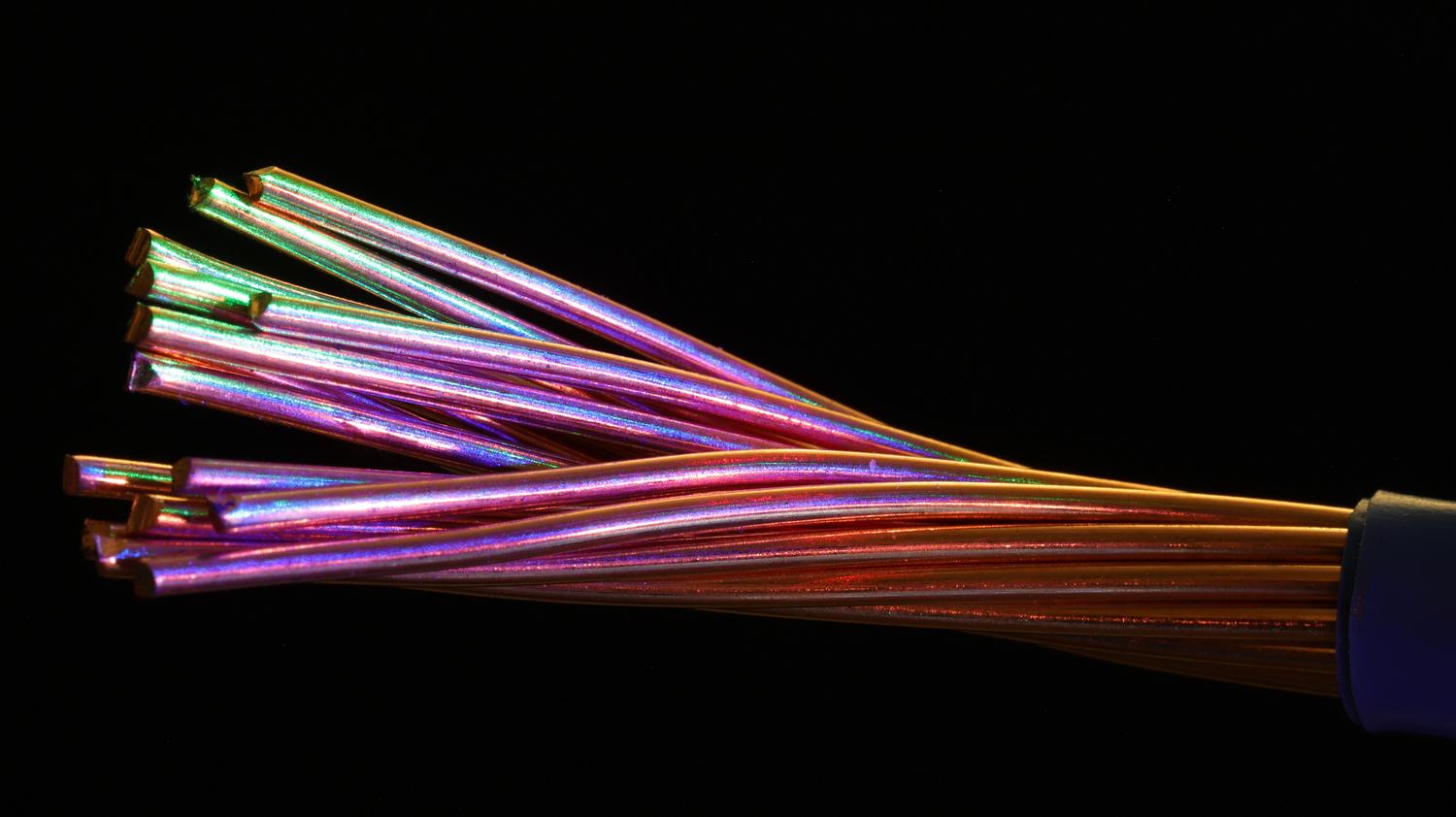 Cables de fibra óptica multicolores iluminados, simbolizando la estabilidad y velocidad de la conexión por fibra frente al 5G.