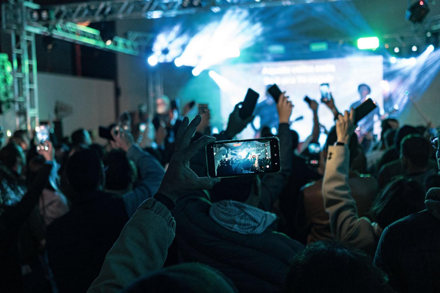 Multitud en un concierto utilizando smartphones simultáneamente, ilustrando la saturación de las antenas en lugares concurridos.