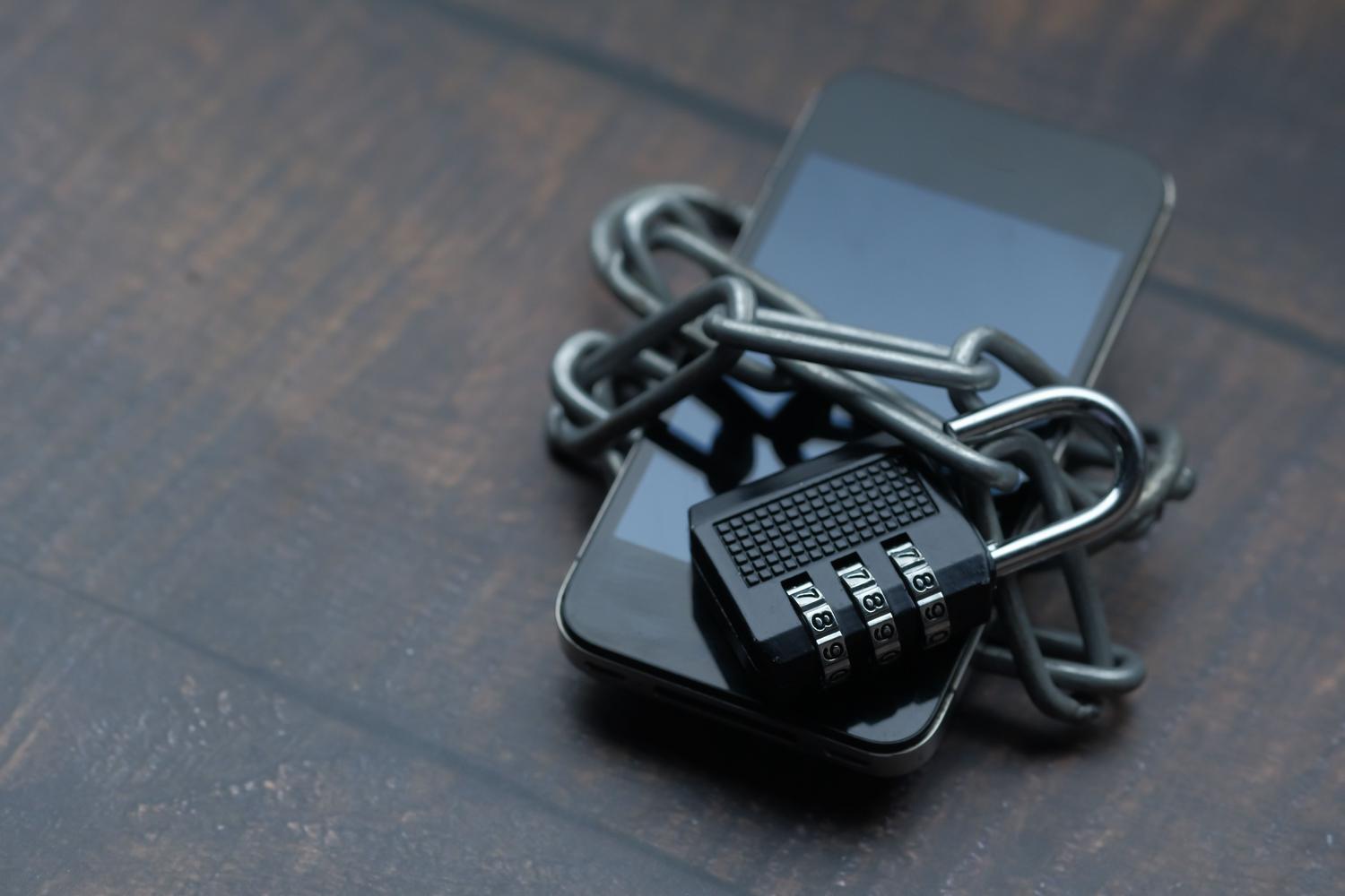 Teléfono móvil protegido con un candado y cadenas, simbolizando la ciberseguridad y el blindaje de la cuenta con verificación en dos pasos