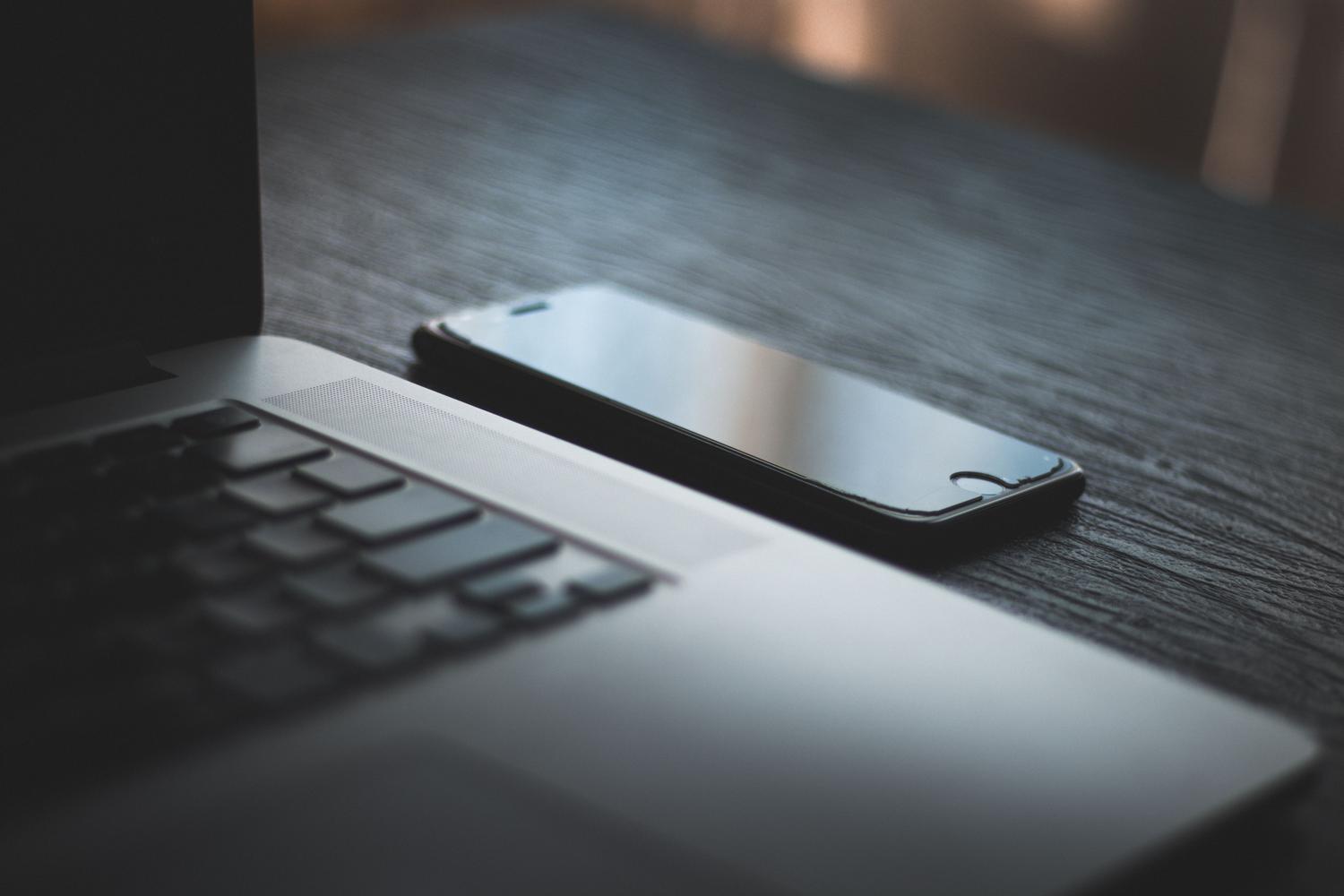 Smartphone y ordenador portátil sobre una mesa, ilustrando la conexión de WhatsApp Web y dispositivos vinculados