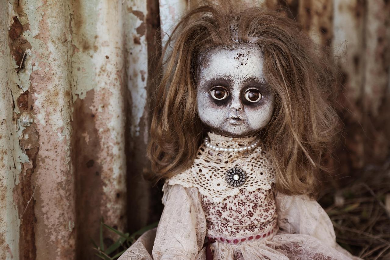 Primer plano de una muñeca antigua y espeluznante, evocando los personajes de cuentos infantiles deformados de Twisted Tower.