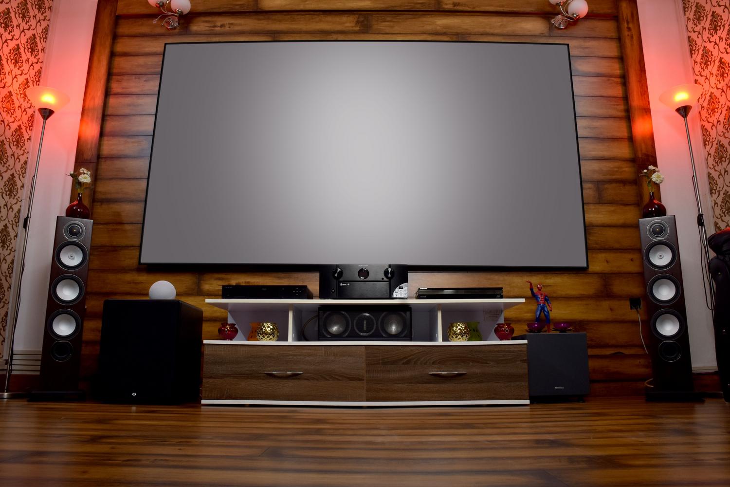 Configuración de cine en casa moderno con dos subwoofers situados a los lados del mueble para una mejor distribución del sonido.