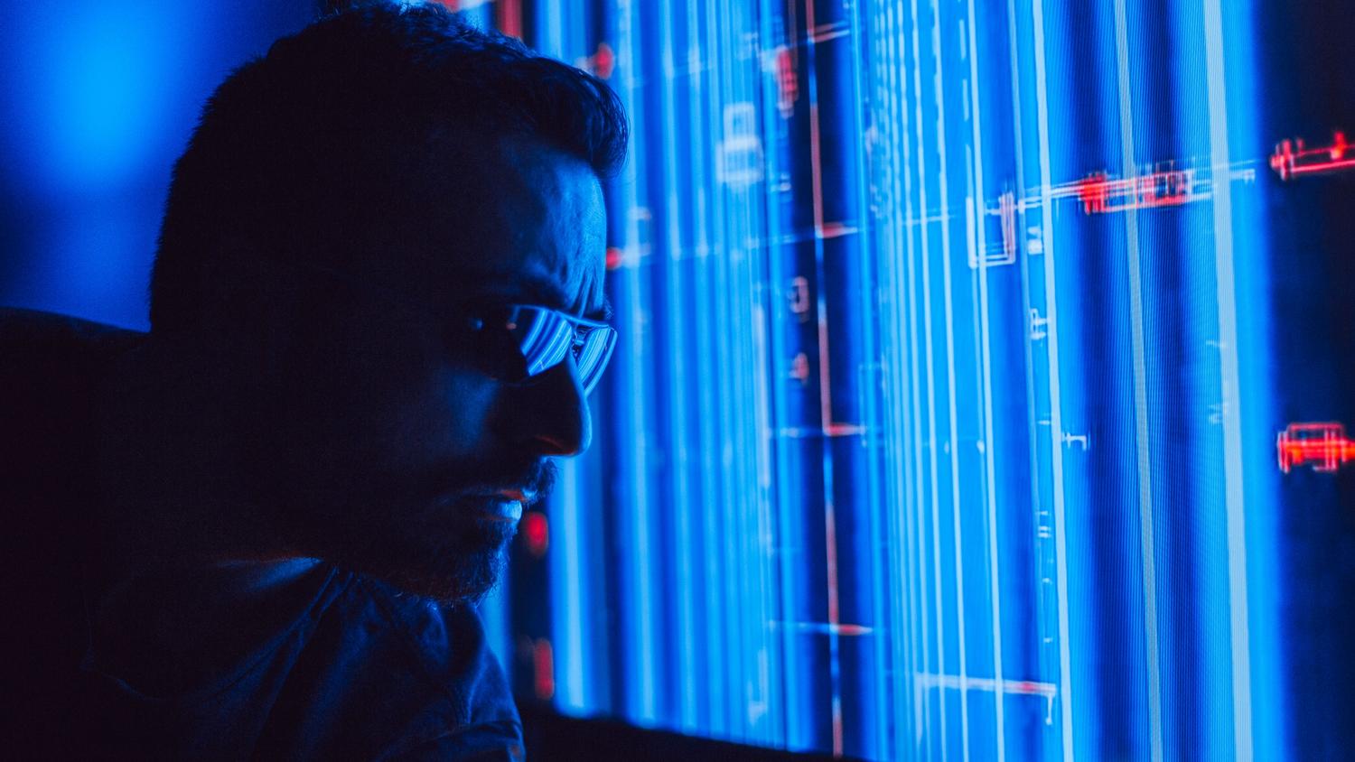 Hombre analizando una pantalla holográfica azul, representando la detección de anomalías y la defensa activa mediante inteligencia artificial.