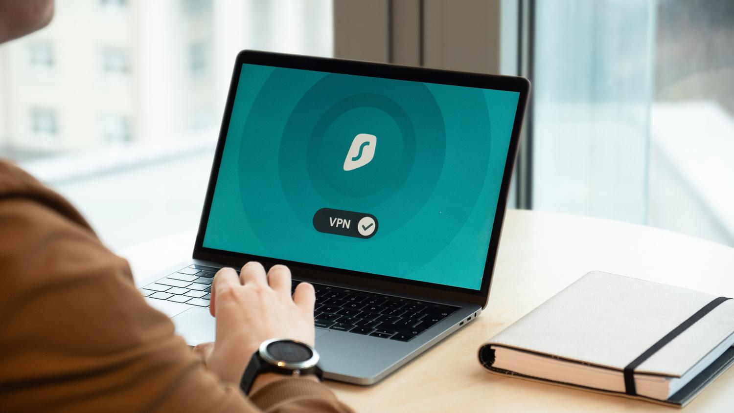 Persona utilizando una aplicación de VPN en un portátil en una oficina moderna, representando el acceso remoto seguro y la IP dedicada en entornos corporativos.