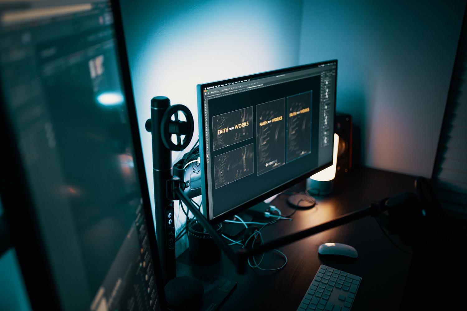 Espacio de trabajo profesional de diseño gráfico utilizando un brazo doble para monitores que mejora la ergonomía y la visibilidad.